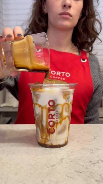 Corto önlüklü barista latte hazırlıyor